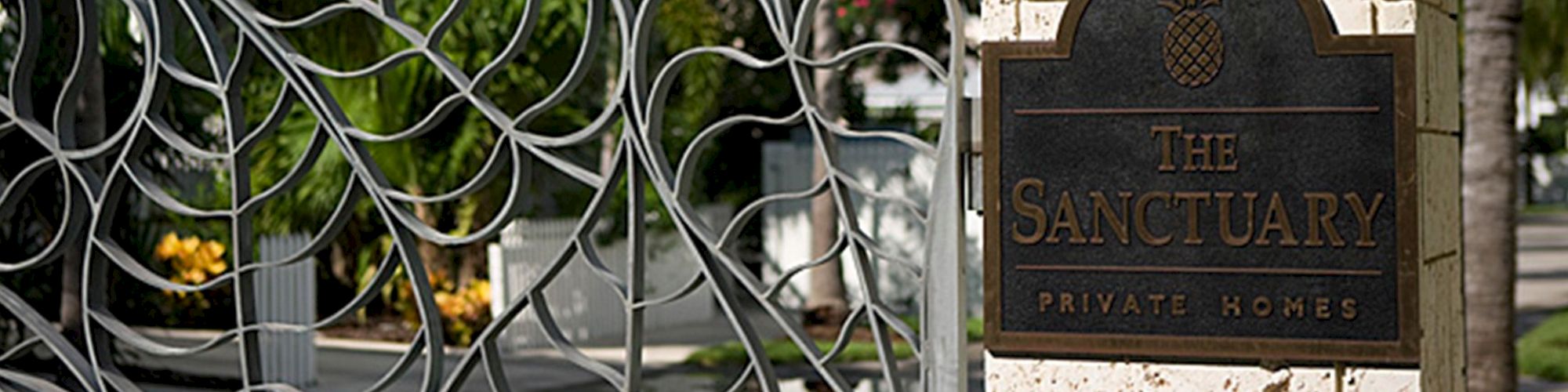 A decorative gate and a sign reading "The Sanctuary Private Homes" set against a stone pillar with lush greenery in the background end the sentence.