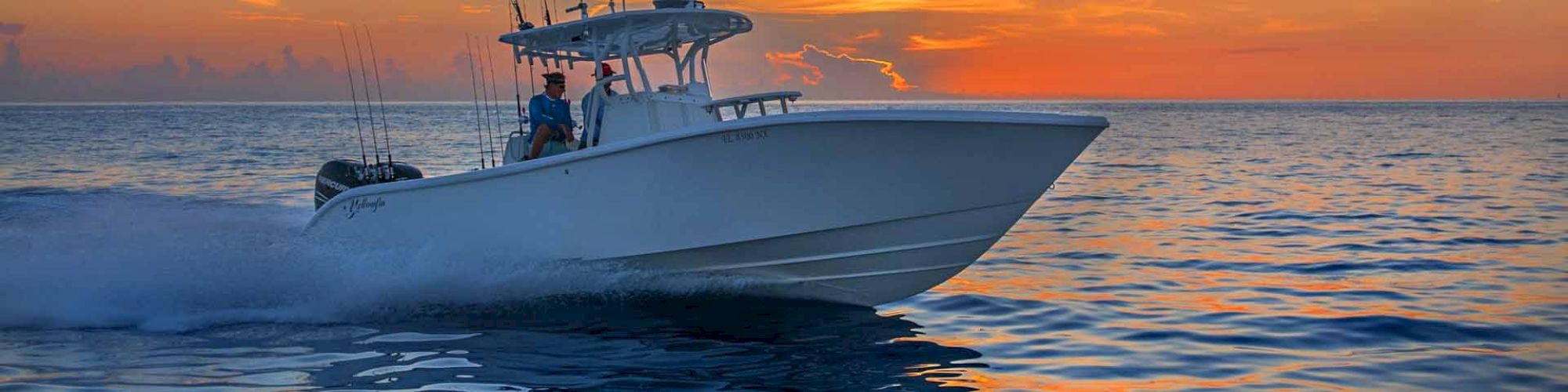 A speed boat moving across the water during a stunning sunset, with a calm ocean and vibrant sky in the background, ending the sentence.