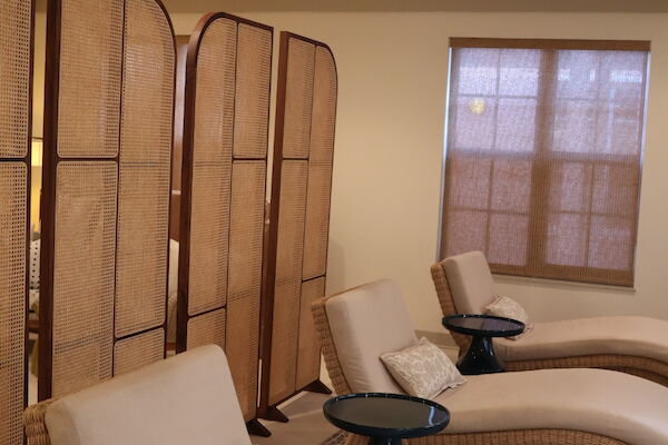 The image shows a relaxing spa room with lounge chairs, pillows, side tables, and a partition screen under soft lighting.