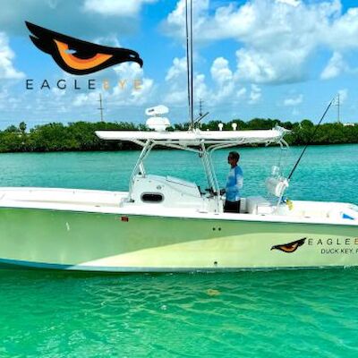 A fishing boat labeled "Eagle Eye" on clear turquoise water, with one person aboard. A logo with an eagle eye is visible.