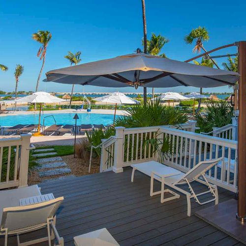 A relaxing poolside scene with lounge chairs, umbrellas, and palm trees, offering a clear view of the pool and a tranquil outdoor environment.